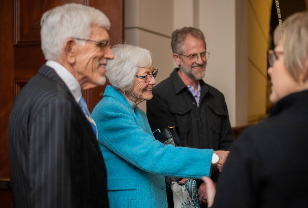 A woman smiles and shakes hands with other guests
